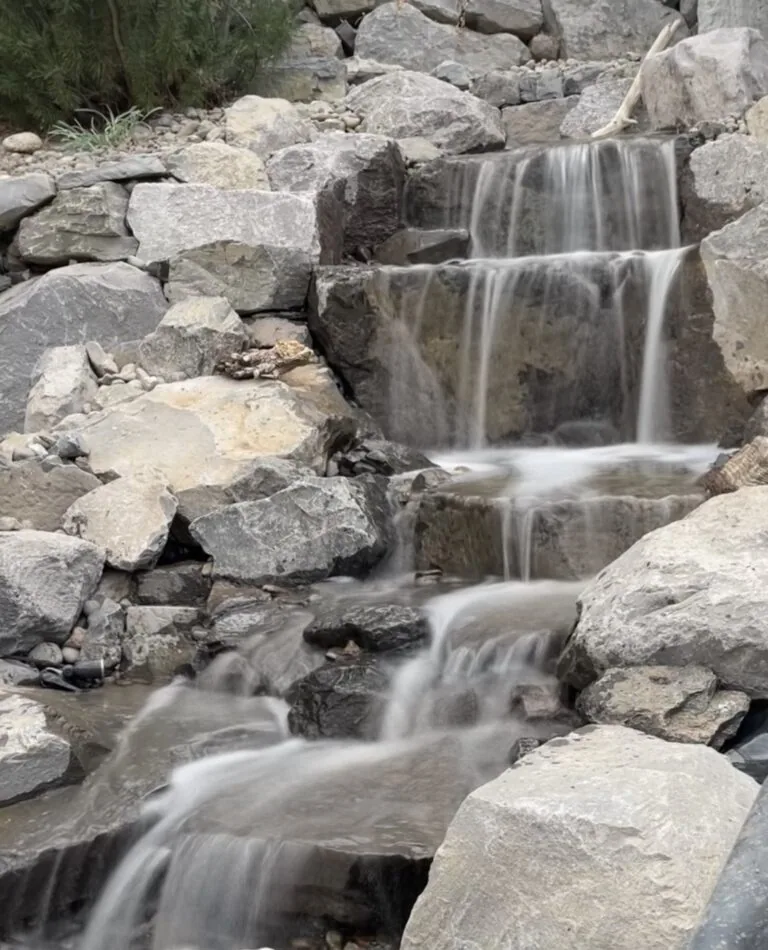 A rock waterfall spilling down several ledges into a pool